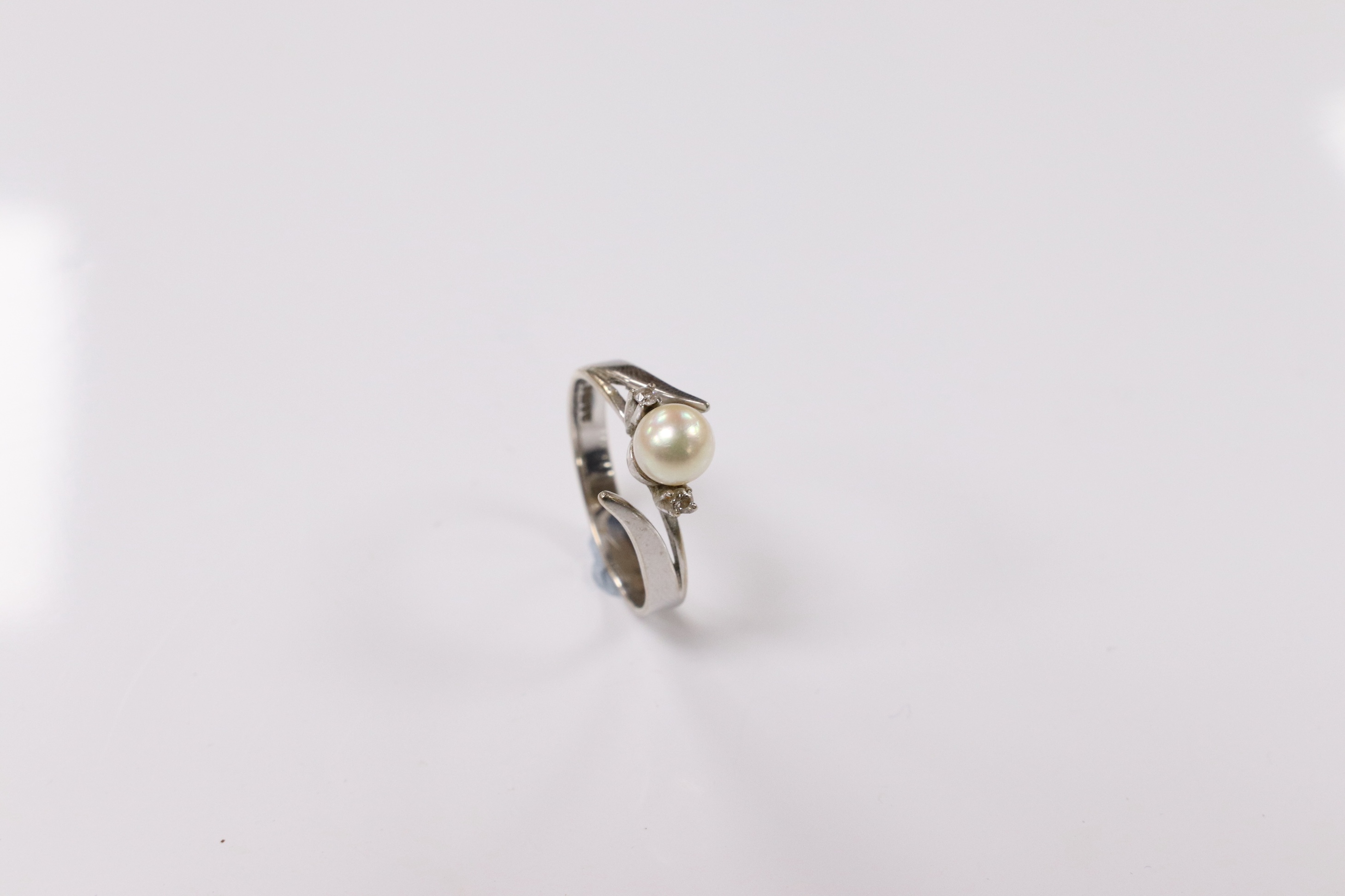 A modern 18ct white gold and single stone cultured pearl set ring, with two stone diamond set shoulders, size Q, gross weight 3.7 grams. Condition - poor to fair